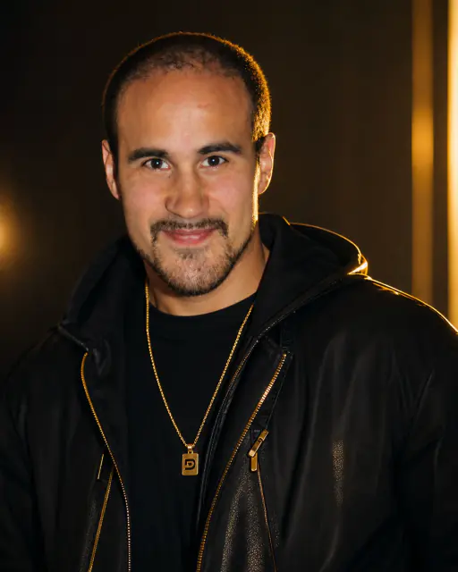 Warm-lit headshot of Deejay Tin'Ok in leather jacket and gold chain - London-based DJ specialising in afrobeats